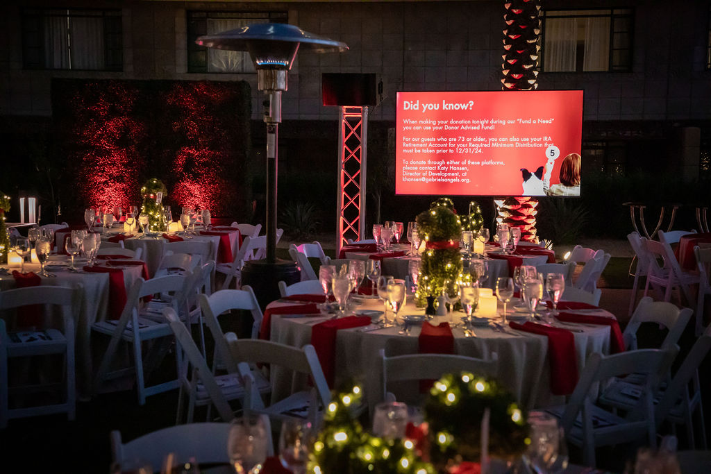 Elegant event table setting with Christmas greenery, red accents, and candlelight